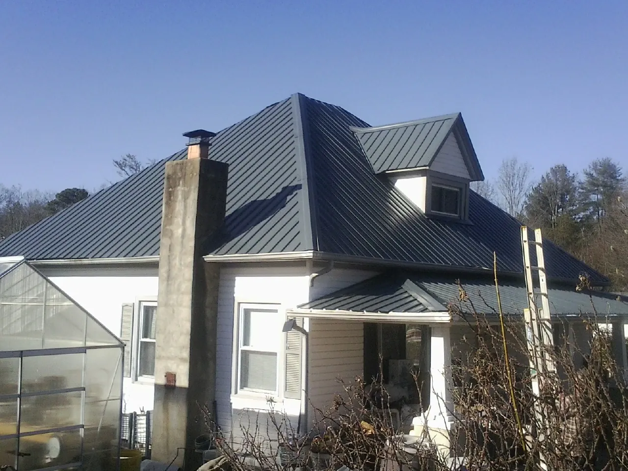 Dark blue standing seam metal roof on a white farmhouse with dormer — Slate & Tile Roof Repair by Roofing Brothers in Owingsville