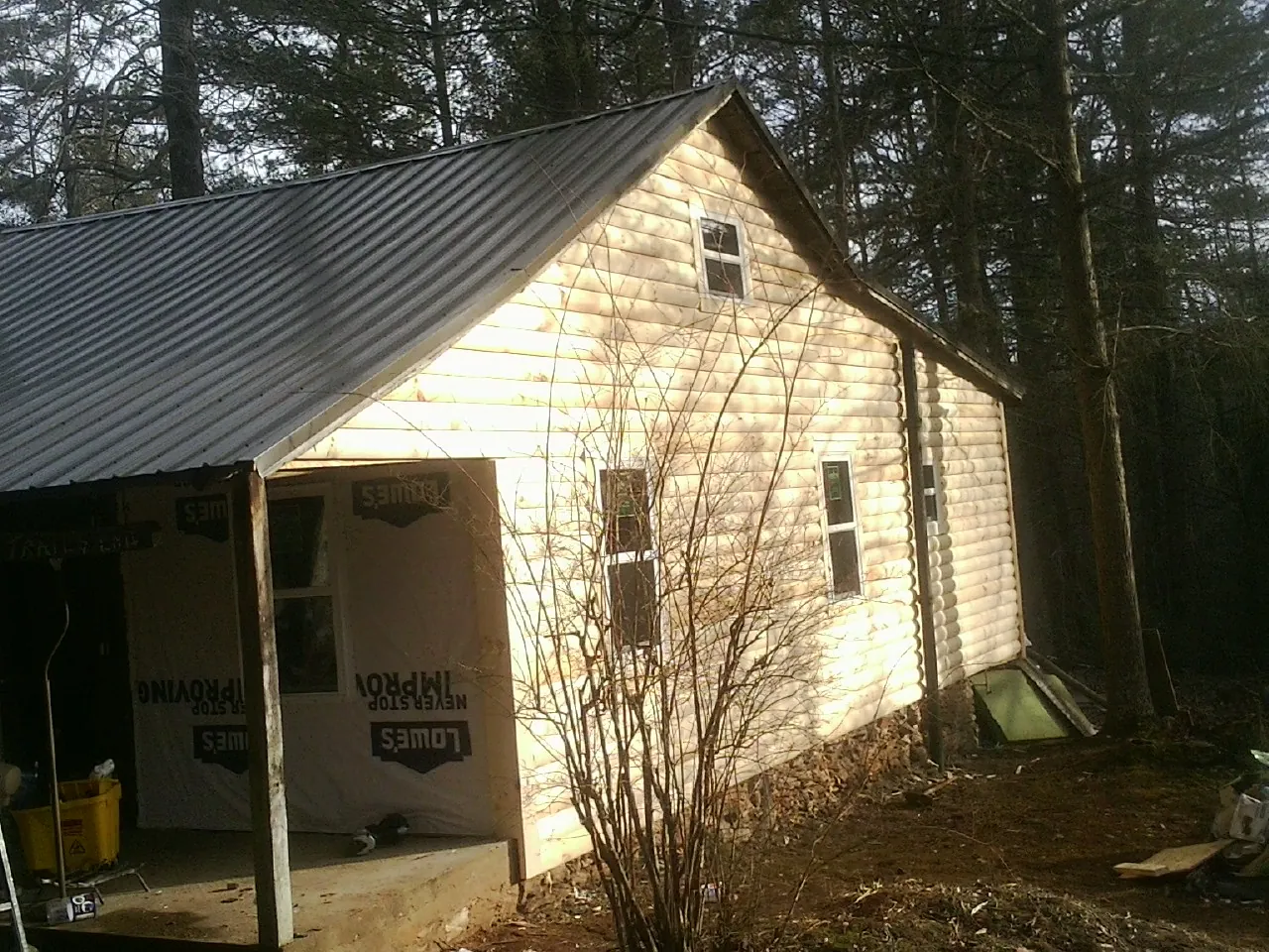 Log siding gable end under a dark metal roof edge in Owingsville