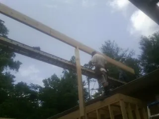 Carpenter setting a ridge beam over a new addition frame — Ice Dam Removal by Roofing Brothers in Owingsville