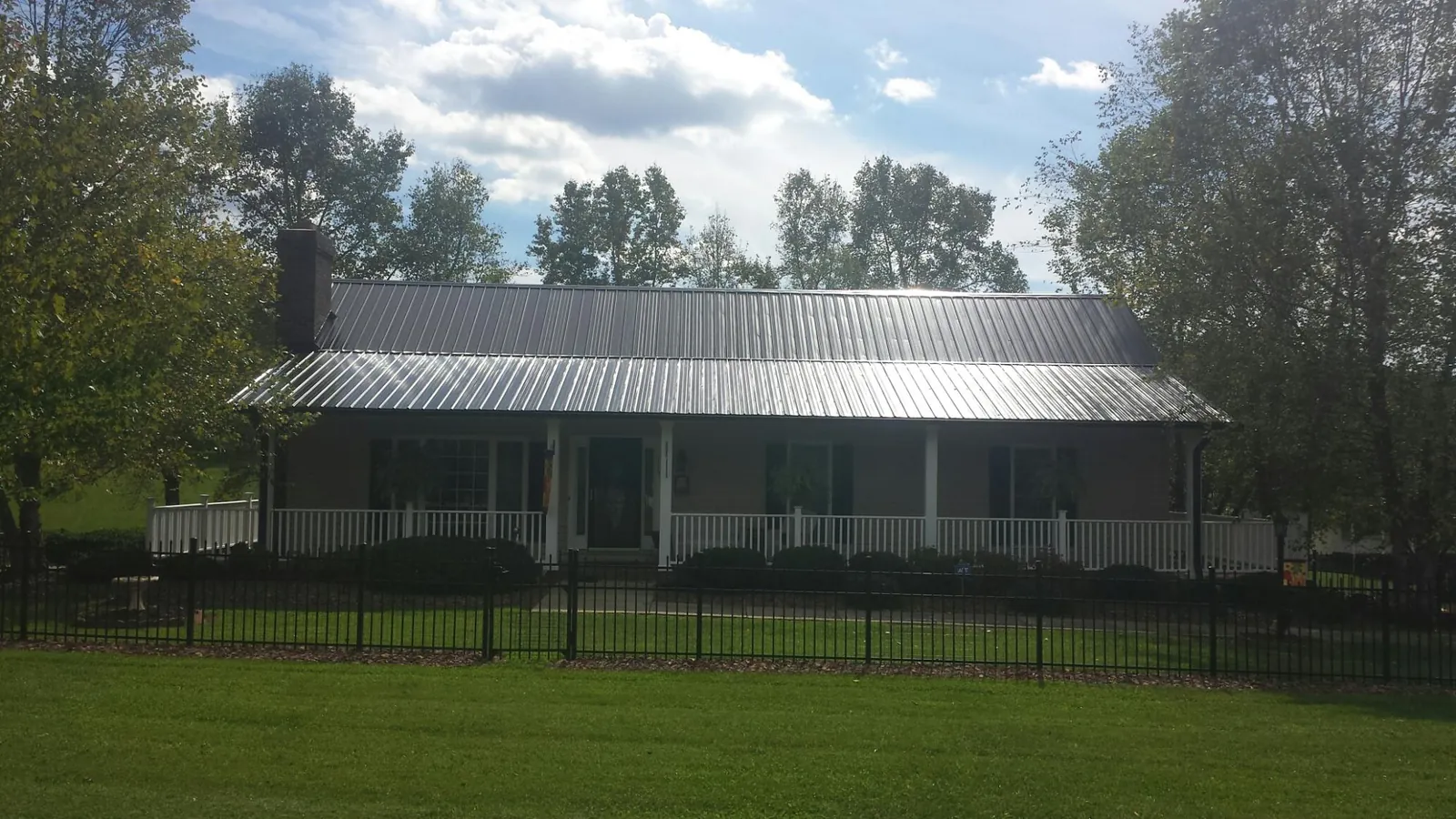 Gray metal roof on a brick ranch with a full width front porch — Gutter Guard Installation work by our crew in Owingsville