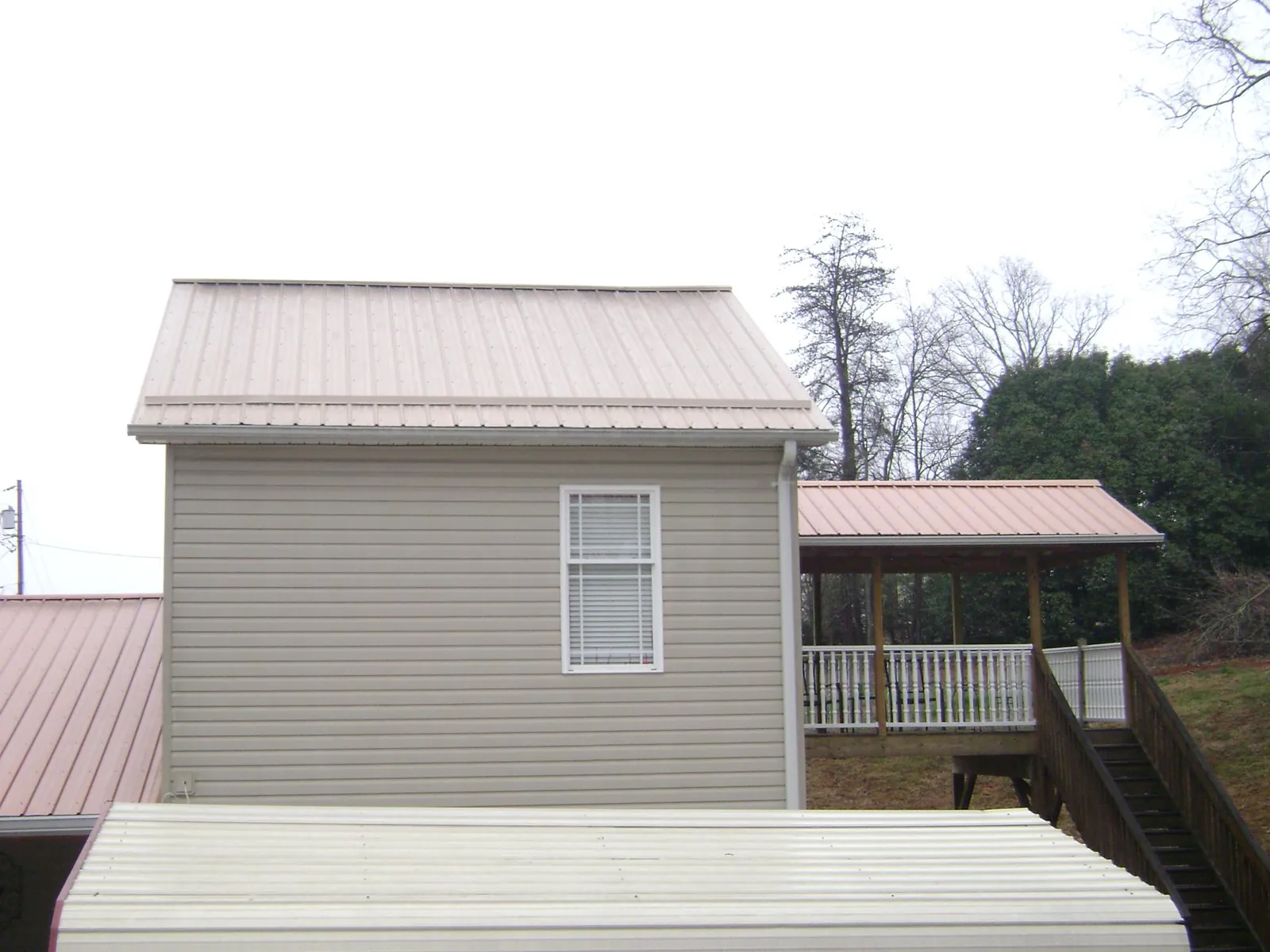 Tan metal roofs on a two story addition and attached porch, from a Roof Replacement job in Owingsville