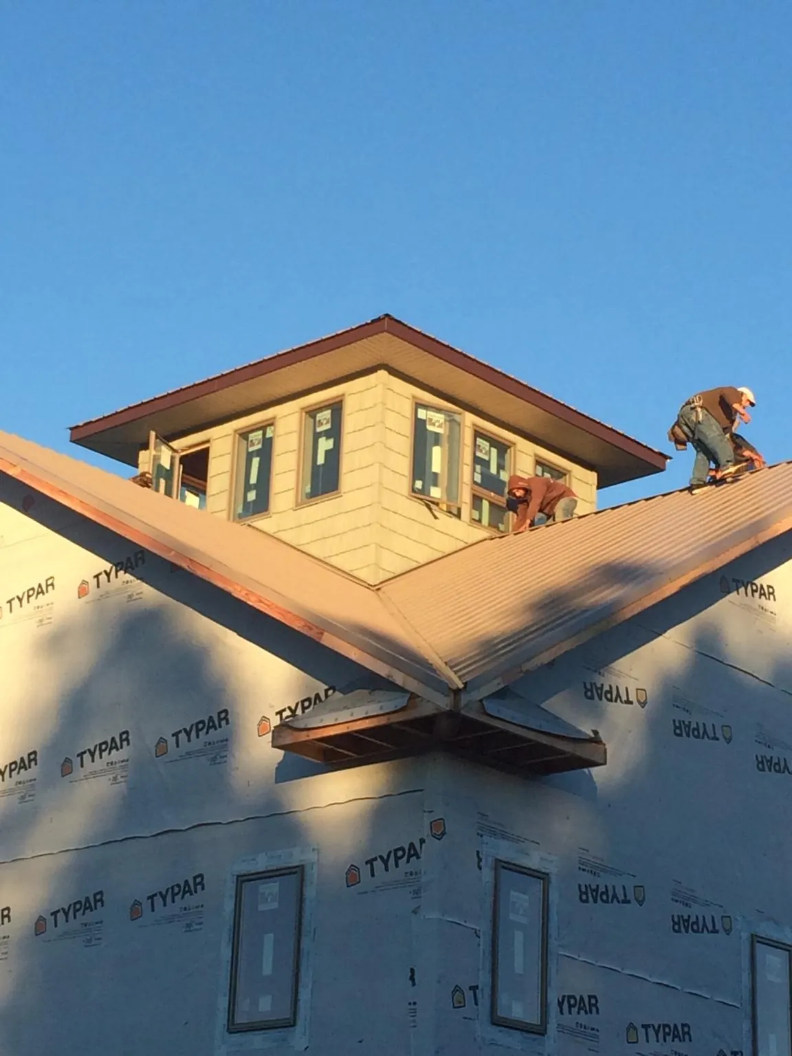 Roofers working around a rooftop cupola on a new metal roof at sunset — Roof Waterproofing in Owingsville by Roofing Brothers